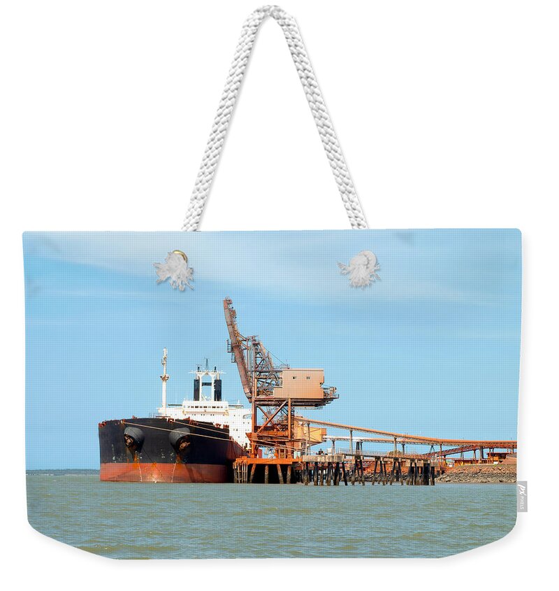 Bauxite Weekender Tote Bag featuring the photograph A 254 meter Ore Carrier Ship unloading Bauxite at Gladstone Harbour, Queensland, Australia. by Geoff Childs