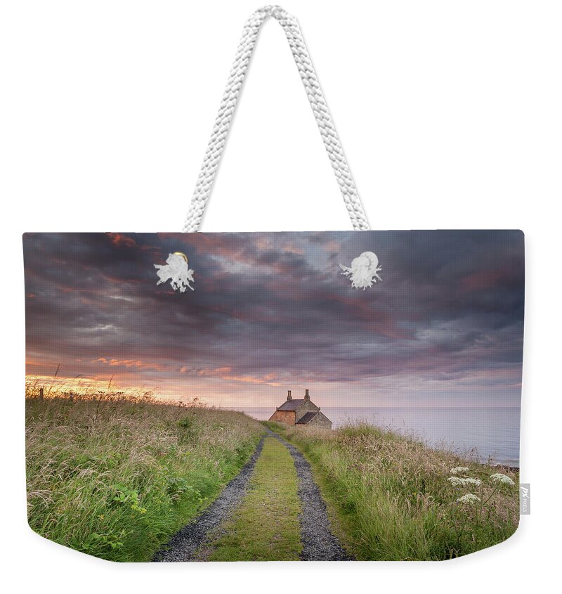 Northumberland Weekender Tote Bag featuring the photograph A cottage by the sea by Anita Nicholson