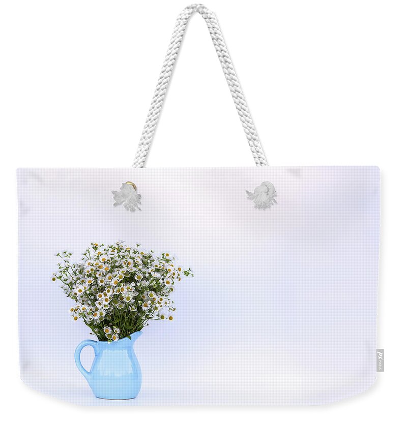 Flower Weekender Tote Bag featuring the photograph Bouquet of small white daisy flowers in a blue ceramic vase by Olga Strogonova