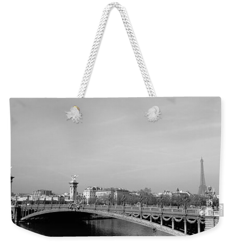 Alexandre Iii Bridge Arch Bridge Building Exterior Building Structure Cloud Black And White Day Eiffel Tower Europe France Horizontal Mediterranean Countries Nobody Outdoors Panoramic Paris Photography River Sky Structure Tower Water Architecture Capital Cities City Location Travel Destinations Weekender Tote Bag featuring the photograph Bridge over a river, Alexandre III Bridge, Eiffel Tower, Paris, France by Panoramic Images