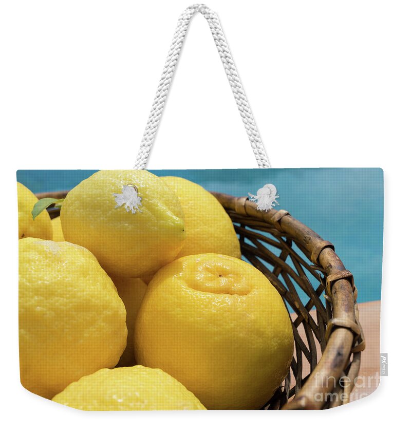 Lemon Tree Weekender Tote Bag featuring the photograph Bright yellow lemons in a basket by the pool by Adriana Mueller