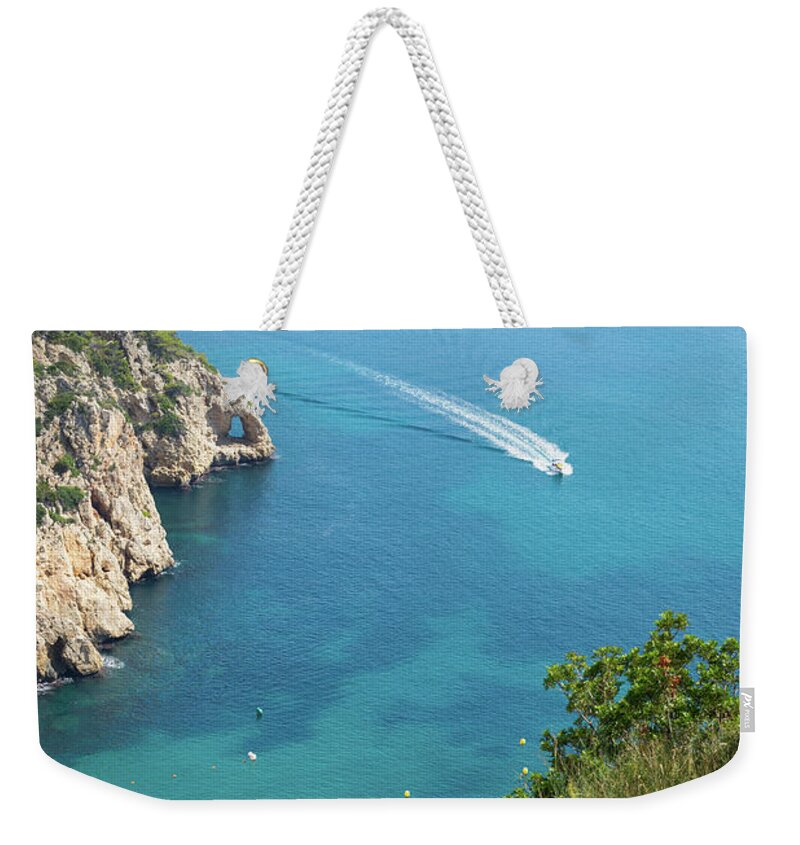 Mediterranean Sea Weekender Tote Bag featuring the photograph Seawater and motor boat. Cala de la Granadella by Adriana Mueller