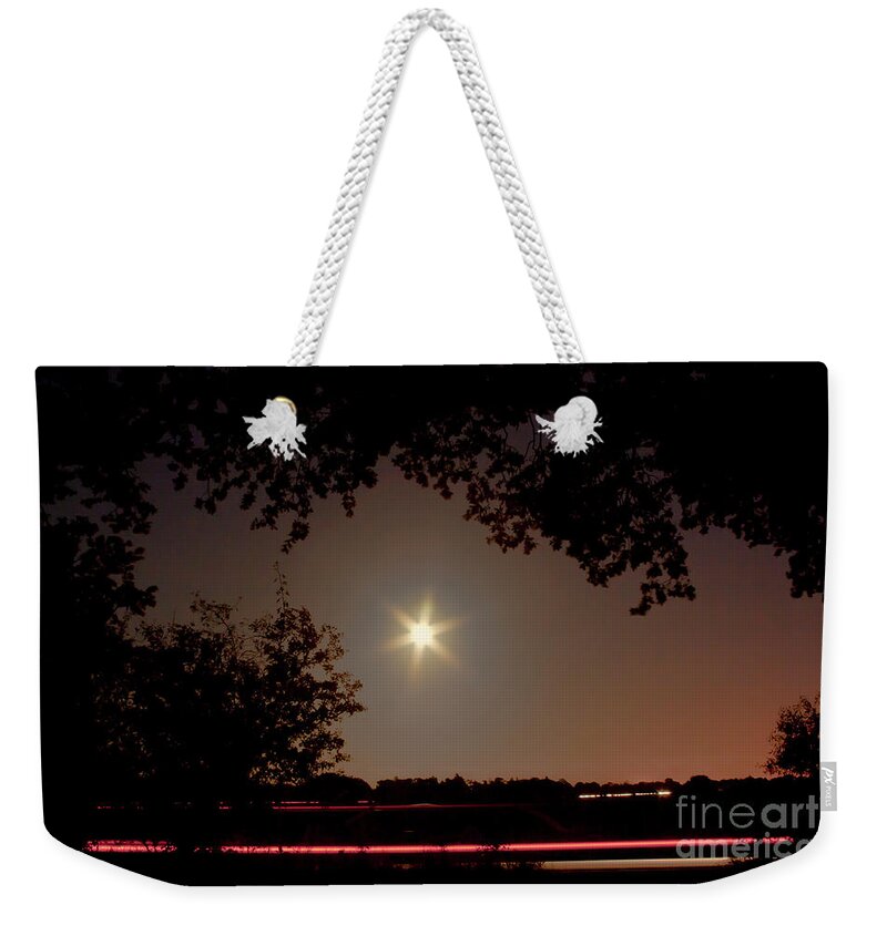 Charming Night Scene Star Rays Ed White Blue Moon Moonscape Dawn Sunset Car Traces Trees Silhouette Sky Stylish Nightscape Landscape Scenic Mood Impressions Emotional Beautiful Delightful Atmospheric Aesthetic Restful Relaxing Balanced Attractive Light Moonlight Serene Minimalist Minimalism Country Road Tranquillity Tranquil Delicate Gentle Magical Impressive Untroubled Peaceful Painterly Nature Abstract Stunning Expressive Inspirational Poetic Solitary Mindfulness Dreaming Pastoral Darkness Weekender Tote Bag featuring the photograph Charming Night Scene With A Star Shaped Moon Moonscape Moon Still Sunset Red Sky And Car Traces by Tatiana Bogracheva