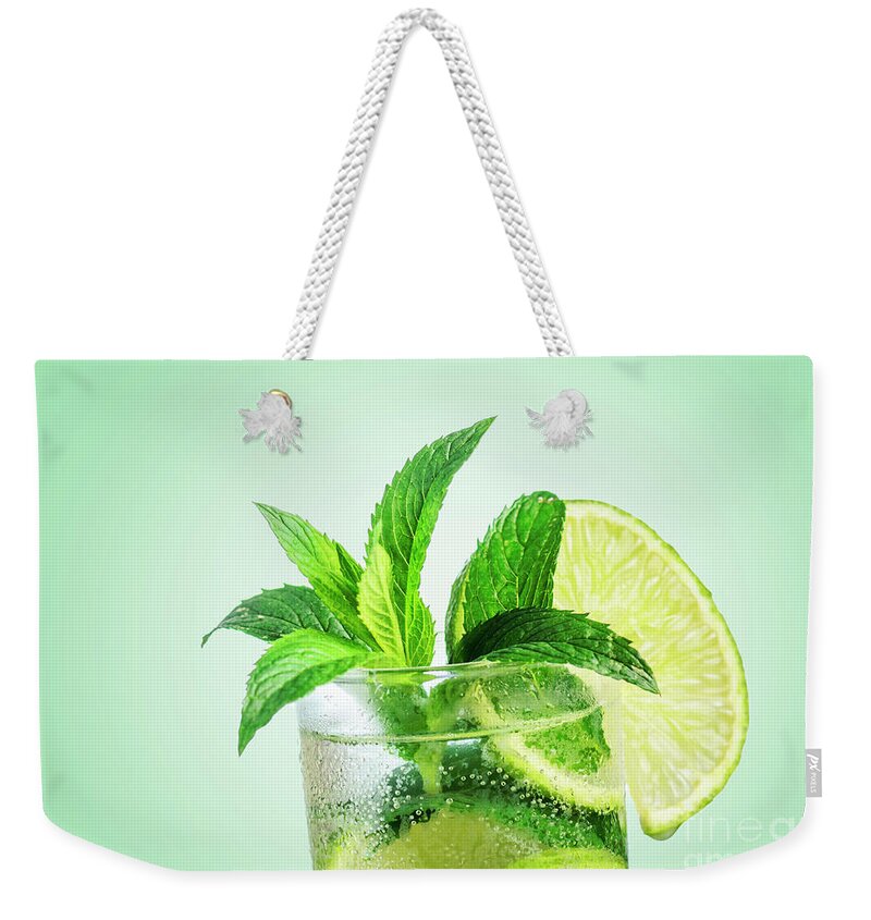 Mojito Weekender Tote Bag featuring the photograph Closeup mojito cocktail with ice isolated over pastel background by Jelena Jovanovic