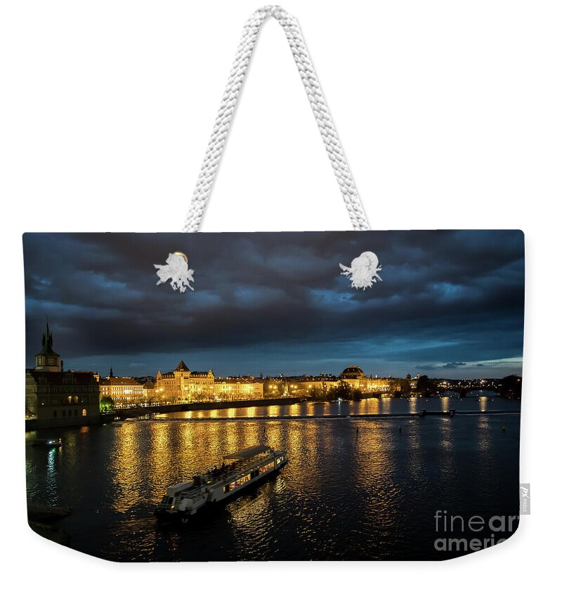Architecture Weekender Tote Bag featuring the photograph Illuminated Moldova River With Ship And Buildings In The Night In Prague In The Czech Republic by Andreas Berthold