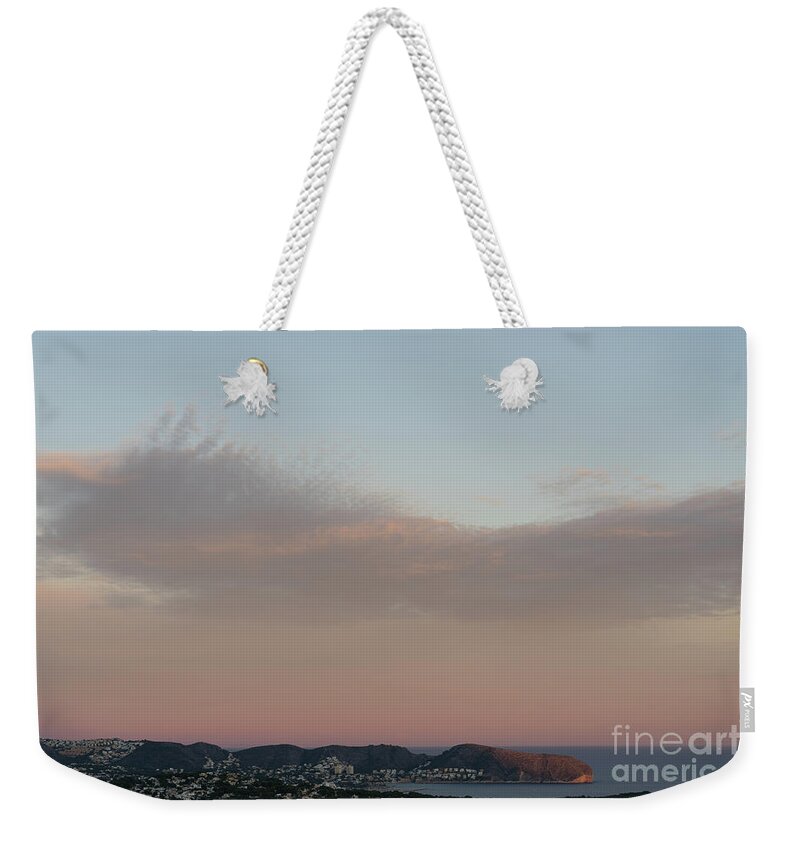 Mediterranean Coast Weekender Tote Bag featuring the photograph Pale pink sky and soft clouds at sunset on the Mediterranean coast by Adriana Mueller