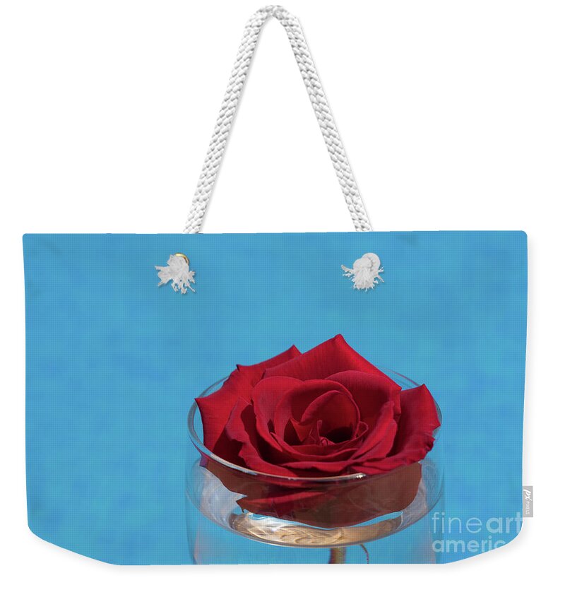 Red Rose Weekender Tote Bag featuring the photograph Red rose blossom and blue water by Adriana Mueller