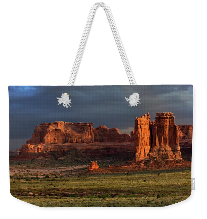 Arches National Park Moab Utah Sunset Red Rock Balanced Rock Hoodoos Towers Weekender Tote Bag featuring the photograph Storm Light at Courthouse Towers by Dan Norris