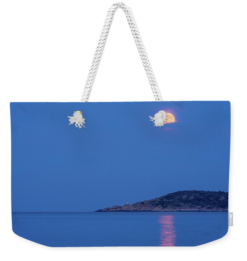 Moon Weekender Tote Bag featuring the photograph Supermoon rising behind clouds above the sea by Alexios Ntounas