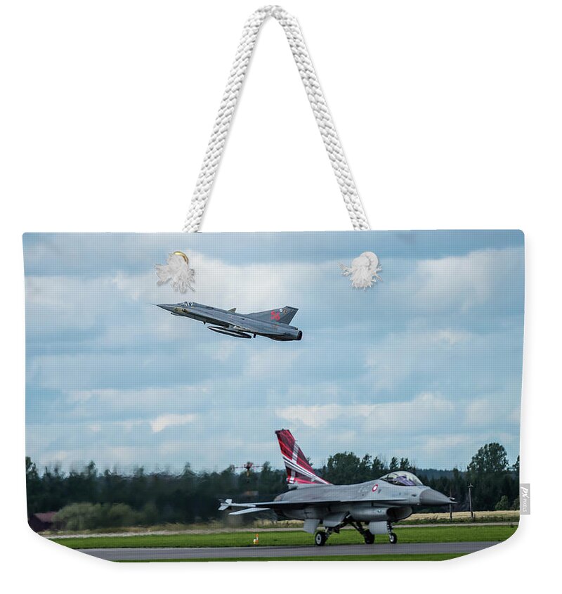 Take Off Weekender Tote Bag featuring the photograph The retired Swedish J35 Draken take off and the taxing Danish F16 Fighting Falcon by Torbjorn Swenelius