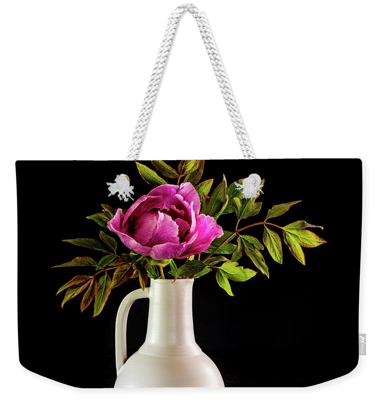 Tree Peony Weekender Tote Bag featuring the photograph Tree peony Lan He Paeonia suffruticosa rockii in a white vase on a black background by Torbjorn Swenelius