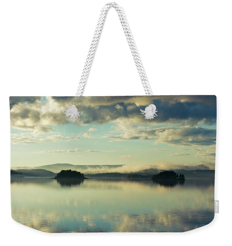 Autumn Weekender Tote Bag featuring the photograph Two islands and the cloudy sky are reflected in a glassy lake by Ulrich Kunst And Bettina Scheidulin