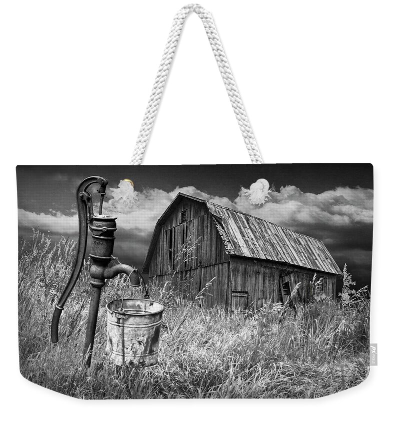 Pump Weekender Tote Bag featuring the photograph Weathered Wooden Barn with Water Pump and Metal Bucket in Black and White by Randall Nyhof