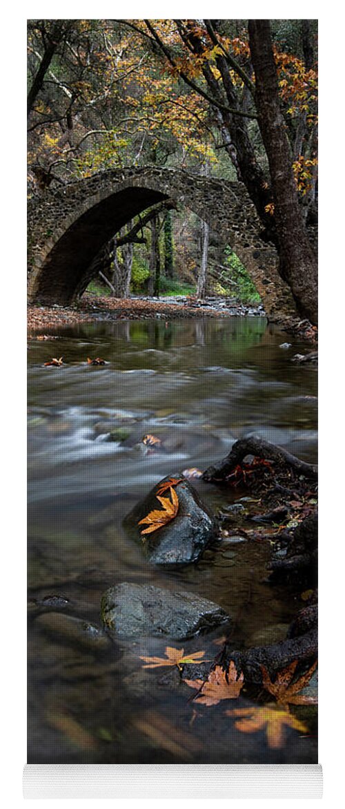 Autumn Yoga Mat featuring the photograph Autumn landscape with river flowing under a stoned bridge by Michalakis Ppalis