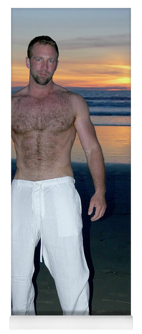 Nude Yoga Mat featuring the photograph Handsome and sexy hairy man stands on the beach as the sun sets behind him. by Gunther Allen
