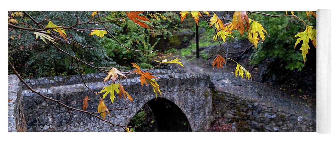 River Yoga Mat featuring the photograph Medieval stoned bridge water flowing in the river in autumn. by Michalakis Ppalis