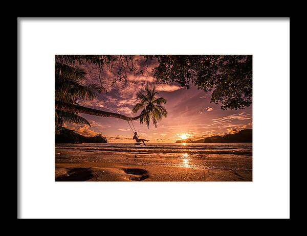 Tropical Tree Framed Print featuring the photograph Carefree woman swinging above the sea at sunset beach. #2 by BraunS