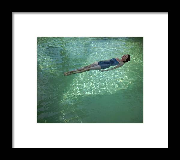 Exterior Framed Print featuring the photograph A Model Floating In A Swimming Pool by John Rawlings