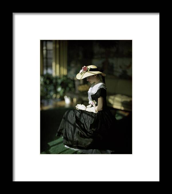 Fashion Framed Print featuring the photograph A Model Wearing A Black Dress And Sun Hat by John Rawlings