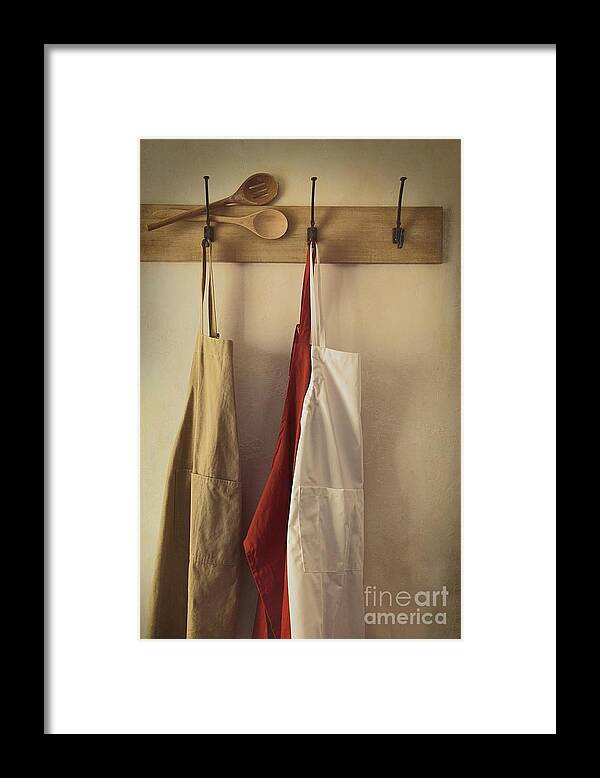 Accessories Framed Print featuring the photograph Aprons hanging on hooks with vintage feel by Sandra Cunningham
