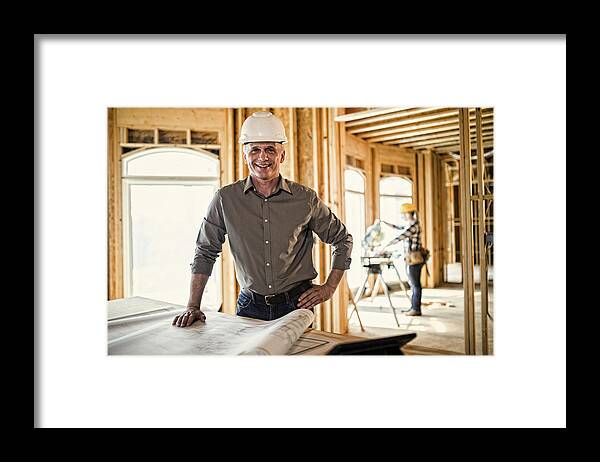 Young Men Framed Print featuring the photograph Architect looking over blueprints by Stevecoleimages