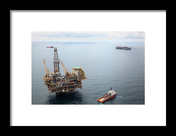 Oil Rig Supply Ship Framed Print featuring the photograph Busy Oil Field by Heliry
