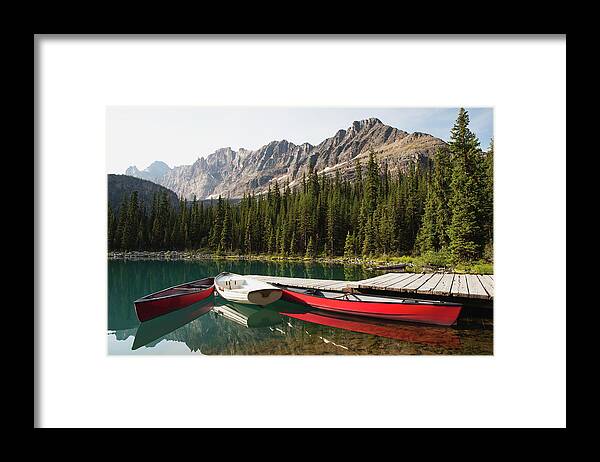 Tranquility Framed Print featuring the photograph Canoes And Rowboat By A Dock On A by Michael Interisano / Design Pics