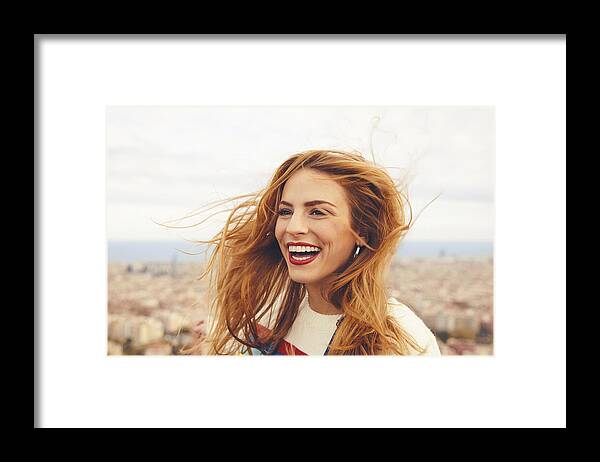 Wind Framed Print featuring the photograph Cheerful woman with tousled hair against cityscape by Nomad