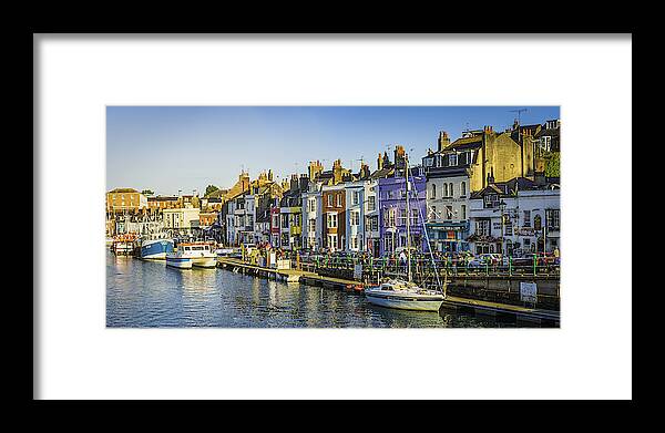 Water's Edge Framed Print featuring the photograph Colourful fishing cottages seaside harbour resort tourists pubs panorama Dorset by fotoVoyager