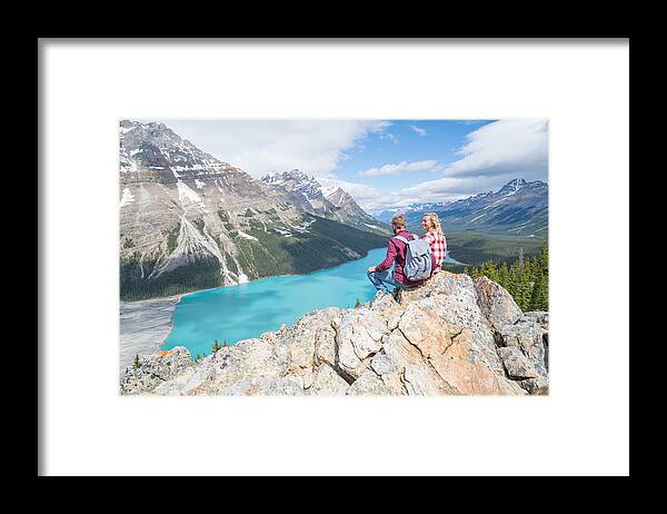 Young Men Framed Print featuring the photograph Couple of hikers overlooking mountain lake by Swissmediavision