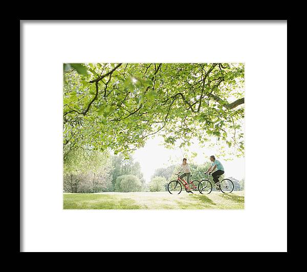 Heterosexual Couple Framed Print featuring the photograph Couple riding bicycles underneath tree by Tom Merton
