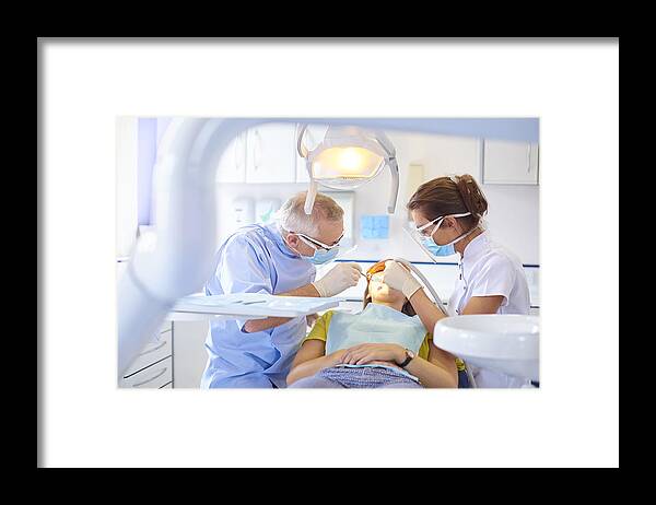 Working Framed Print featuring the photograph Dental team performing procedure by Sturti
