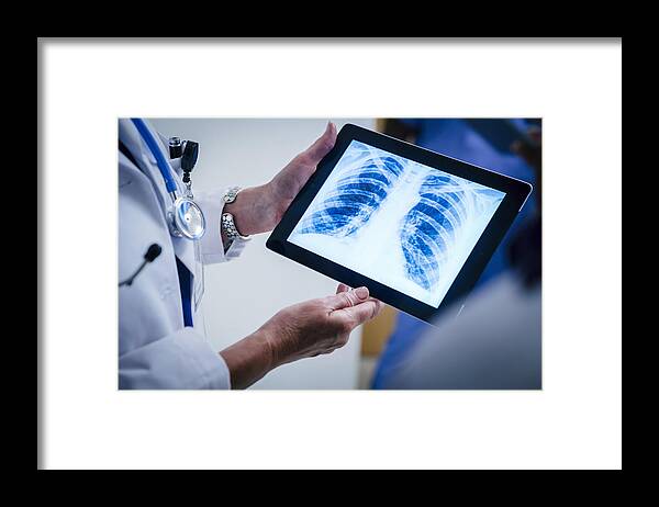 Expertise Framed Print featuring the photograph Doctors examining x-ray of chest and ribs on digital tablet by FS Productions