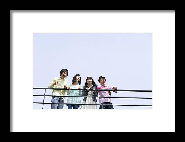 Young Men Framed Print featuring the photograph Four young people leaning on the railing, side by side, low angle view, blue background, copy space, Japan by Daj