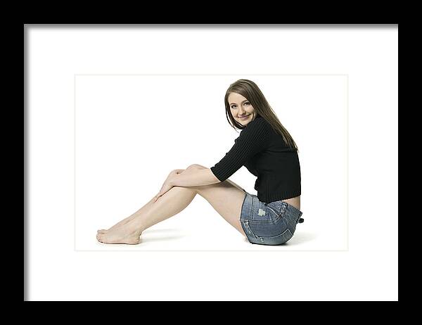 Sweater Framed Print featuring the photograph Full Body Shot Of A Teenage Brunette Female In A Black Sweater As She Sits And Smiles by Photodisc