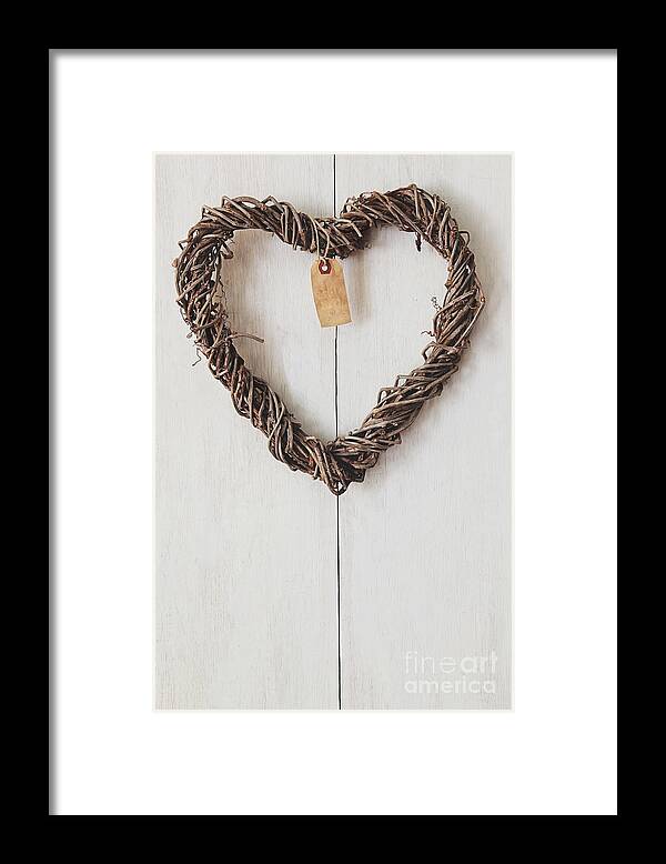Brown Framed Print featuring the photograph Heart wreath hanging on wood background by Sandra Cunningham