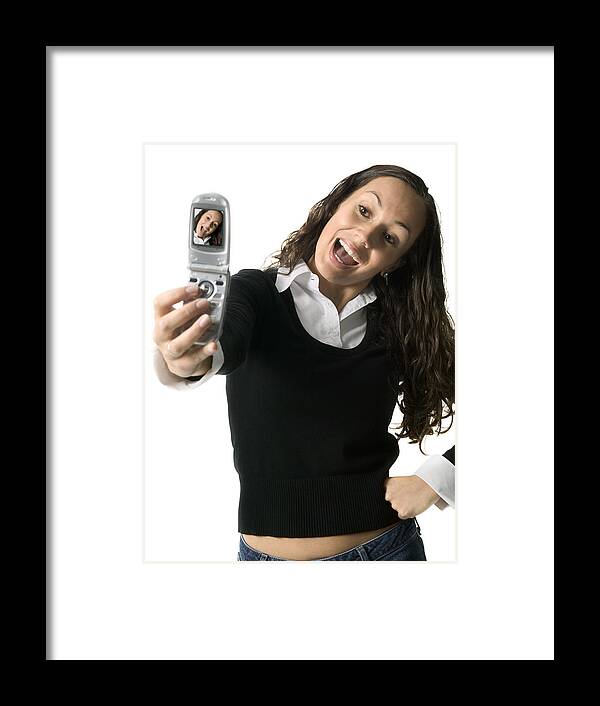 White Background Framed Print featuring the photograph Medium Shot Of A Young Adult Female As She Playfully Poses For Her Camera Phone by Photodisc