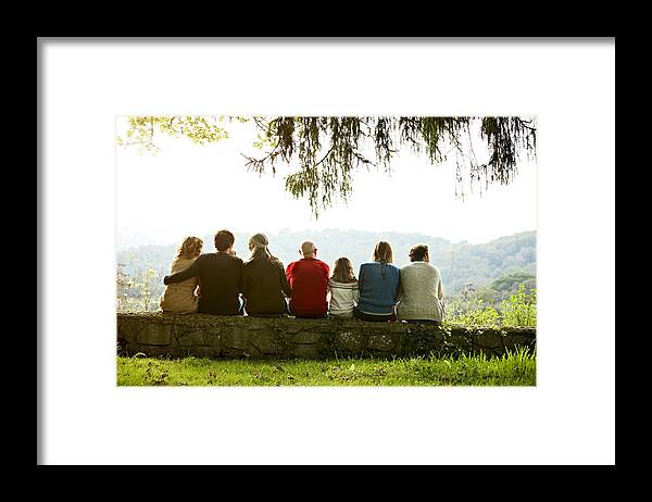 Adult Offspring Framed Print featuring the photograph Multi-generation family relaxing on retaining wall by Morsa Images
