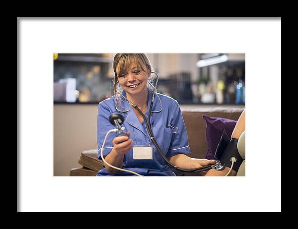 People Framed Print featuring the photograph Nurse takes patients blood pressure on home visit by MartinPrescott