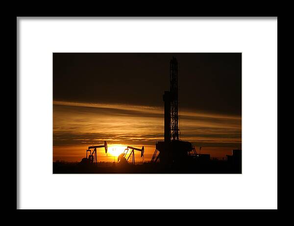 Williston. North Dakota Framed Print featuring the photograph Oil rig and two pumpjacks in the sunset by Jeff Swan