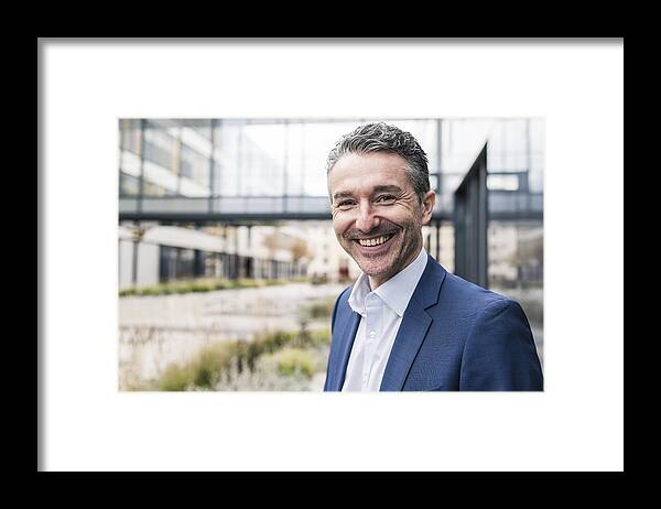 Mature Adult Framed Print featuring the photograph Portrait of smiling businessman outside office building by Westend61