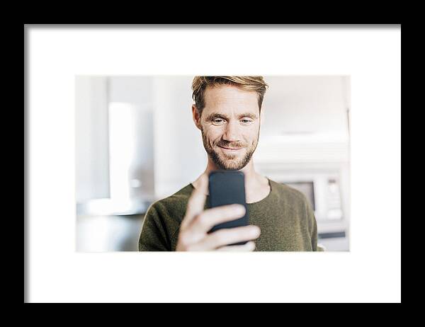 People Framed Print featuring the photograph Portrait of smiling man looking at cell phone by Westend61