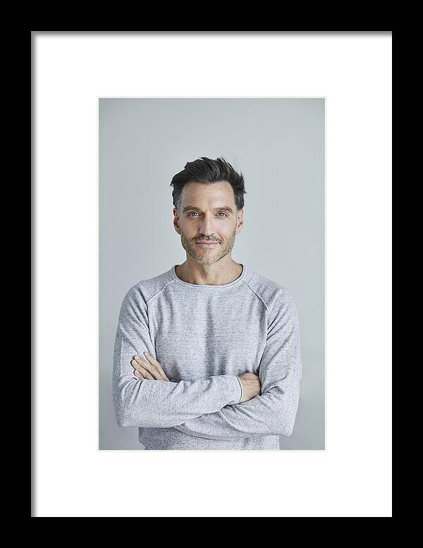 Mature Adult Framed Print featuring the photograph Portrait of smiling man with stubble wearing grey sweatshirt by Westend61