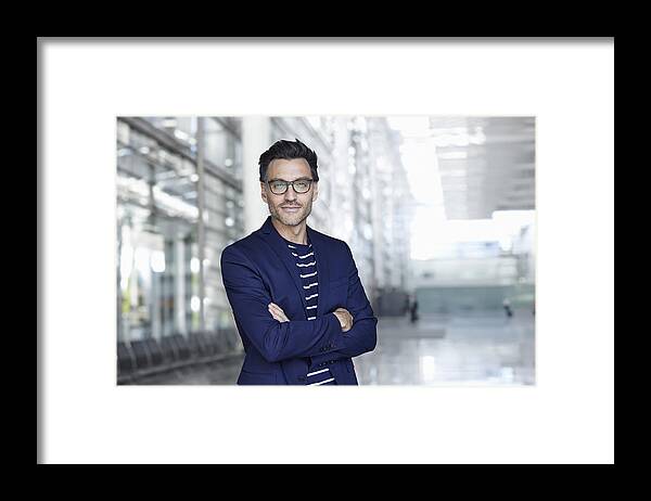 Mature Adult Framed Print featuring the photograph Portrait of stylish businessman with stubble wearing blue suit and glasses by Westend61