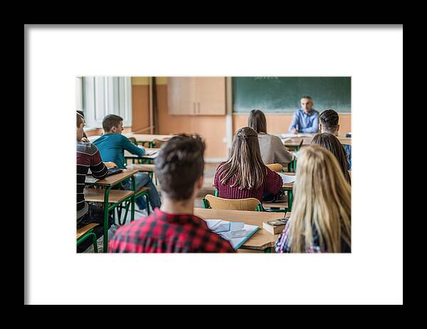 Education Framed Print featuring the photograph Rear view of high school students attending a class. by Skynesher