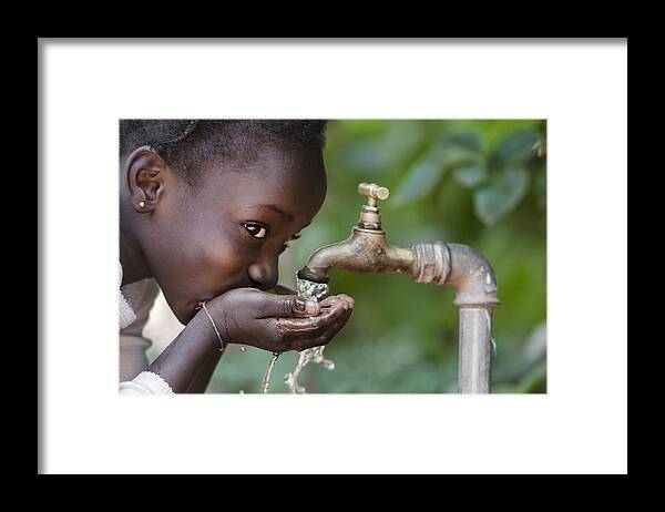 Child Framed Print featuring the photograph Social Issues: African Black Child Drinking Fresh Water From Tap by Borgogniels