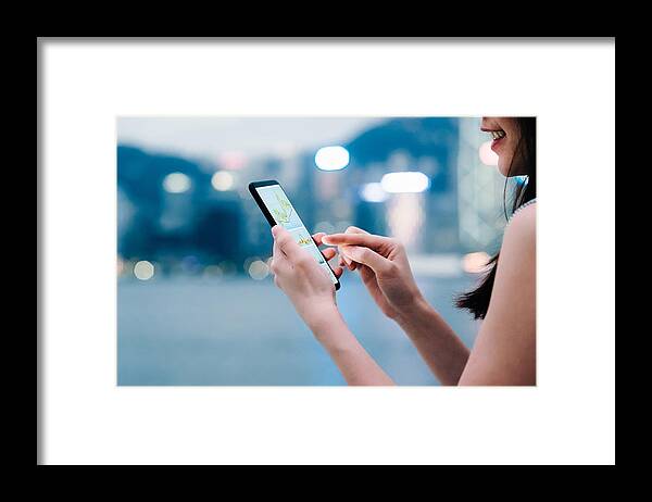 Working Framed Print featuring the photograph Woman checking financial trading data with smartphone in city by D3sign