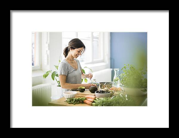 Mature Adult Framed Print featuring the photograph Woman preparing healthy food in her kitchen by Westend61