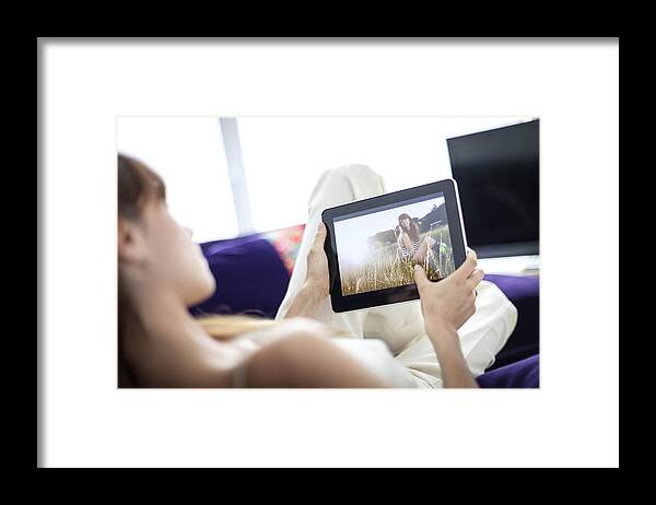 Internet Framed Print featuring the photograph Woman using tablet computer on sofa by Kris Ubach and Quim Roser