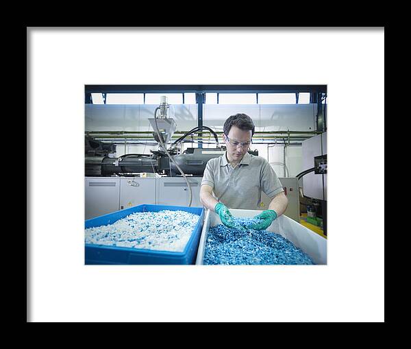 Working Framed Print featuring the photograph Worker inspecting recycled plastic in plastics factory by Monty Rakusen
